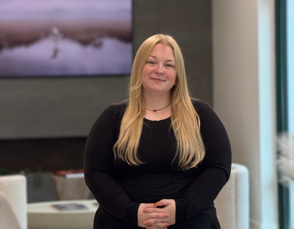 Allison Silva, staff member at Premier Prosthodontics in Raleigh, NC, smiling in the modern dental clinic lobby.